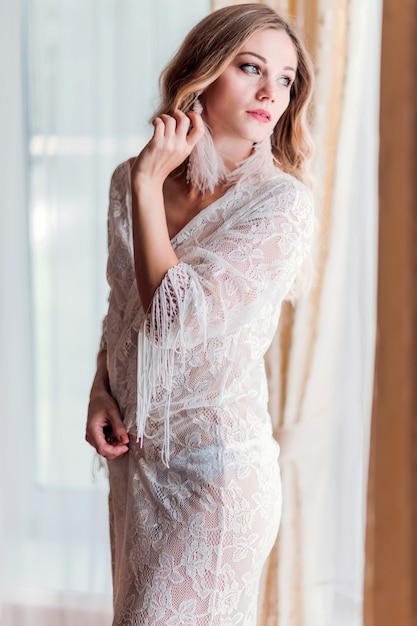 Beautiful bride in a lace robe indoors