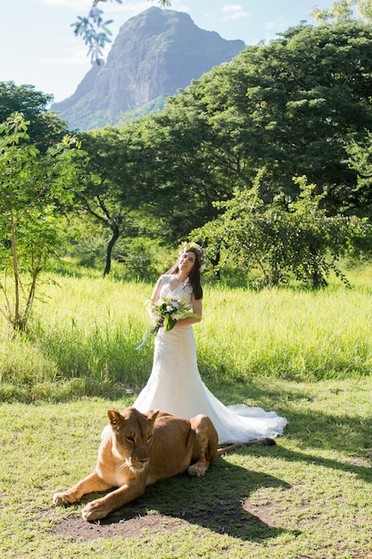 Beautiful bride and a lioness in the picturesque nature