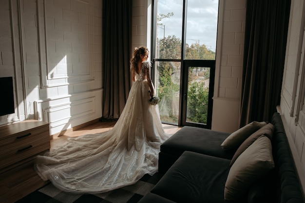 A beautiful bride in a long dress by the window