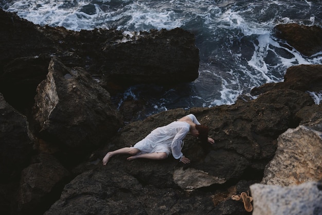 Beautiful bride lying on her back on a rocky seashore Summer vacation concept