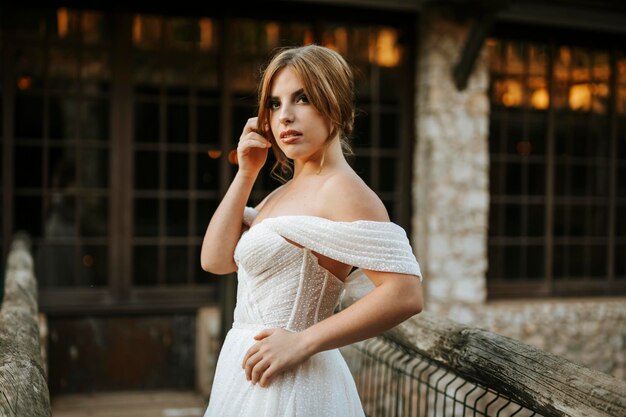 Photo beautiful bride portrait standing on wooden bridge in front of stone building