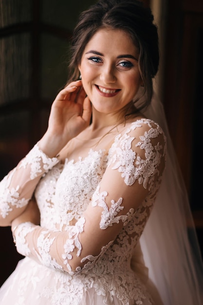 Beautiful bride posing in the wedding morning room Cheerful young gorgeous woman waiting by the groom