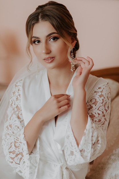 Beautiful bride in robe posing near window, wedding preparation