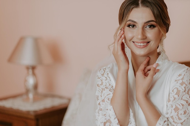 Beautiful bride in robe posing near window, wedding preparation