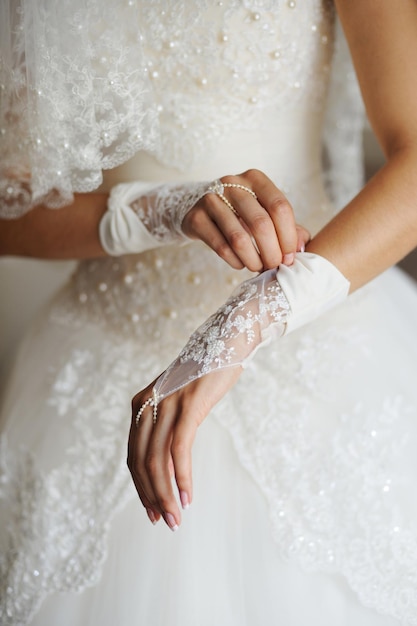 Beautiful bride's hands with manicure in white gloves