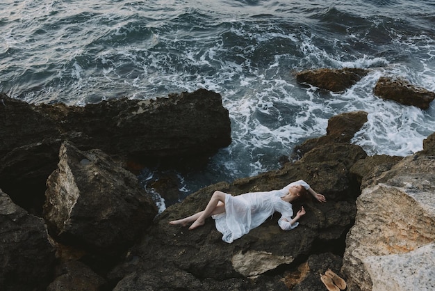 Beautiful bride in a secluded spot on a wild rocky coast in a white dress unaltered