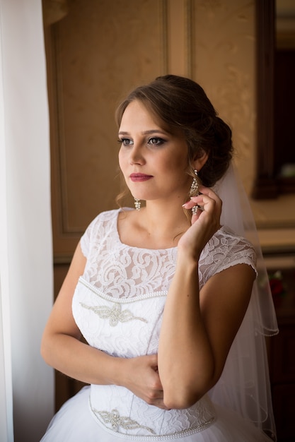 Beautiful bride standing near the window and smiling