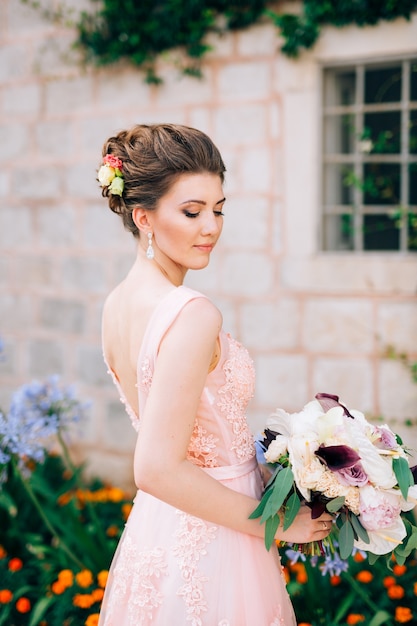 Bella sposa in abito da sposa tenero con bouquet da sposa a perast.