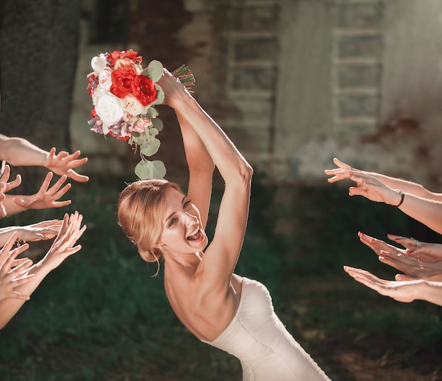 Photo beautiful bride throws wedding bouquet to her friends