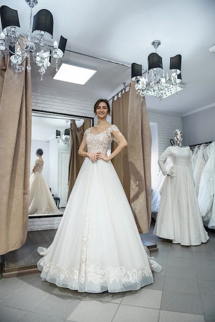 Beautiful bride in wedding dress posing before mirror