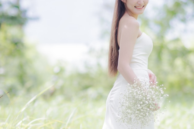 Beautiful bride in wedding dress smiled happily and holding a bouquet of flowers