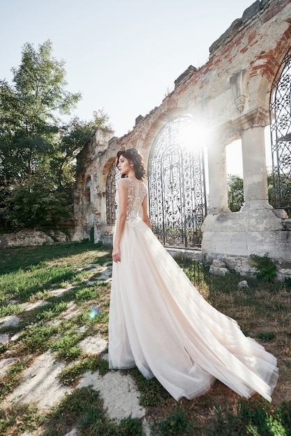 Bella sposa in abito da sposa, che viene fotografato il giorno del matrimonio vicino al vecchio castello.