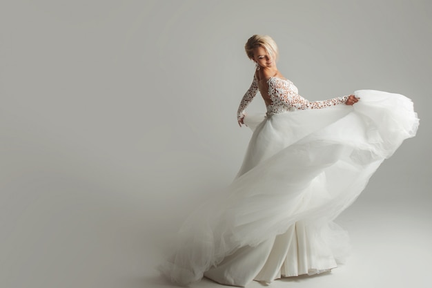 Красивая невеста в свадебном платье с длинной пышной юбкой на белом