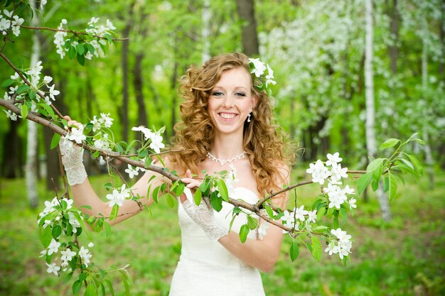 Beautiful bride in a white dress in blooming gardens in the spring