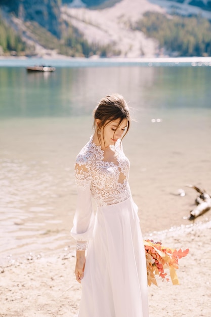 Beautiful bride in a white dress with sleeves and lace with a yellow autumn bouquet of dried flowers