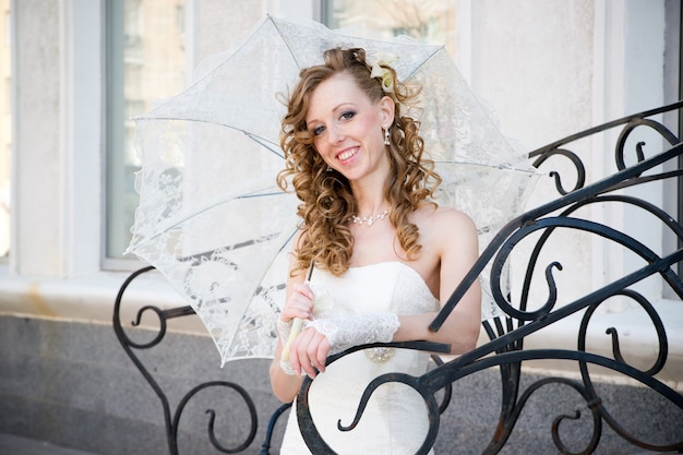 Beautiful bride in white dress with umbrella