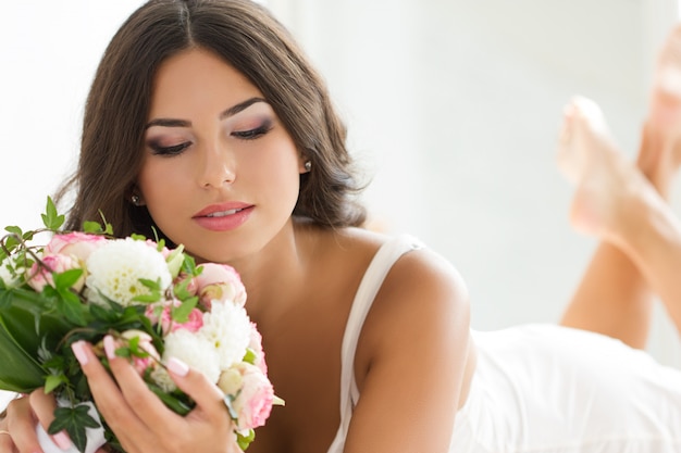 Beautiful bride in white lingerie holding nuptial bouquet