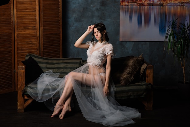 彼女の寝室とスタジオに座っている白いランジェリーの美しい花嫁。結婚式のコンセプトの朝