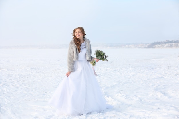 Beautiful bride with bouquet outdoors on winter day