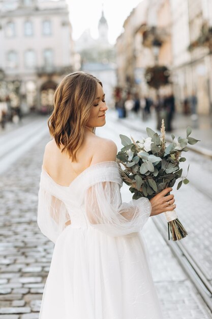 Beautiful bride with a bouquet posing in the city streets