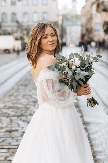 街の通りでポーズをとる花束を持つ美しい花嫁