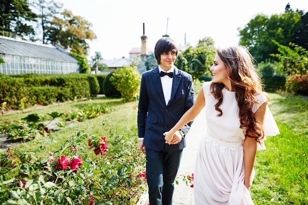 Beautiful bride with curly hair and bridegroom standing close to each other at green leaves, wedding photo, wedding day, portrait.