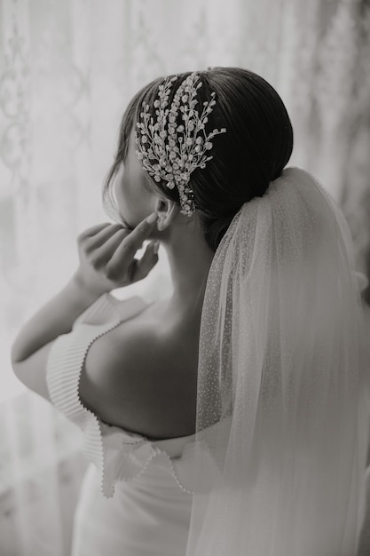 A beautiful bride with a fashionable wedding hairstyle and a luxurious tiara on her head Closeup portrait of a young gorgeous bride in a hotel room High quality photo