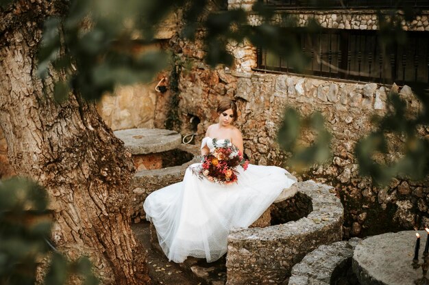 Photo beautiful bride with her bouquet sititng in the garden