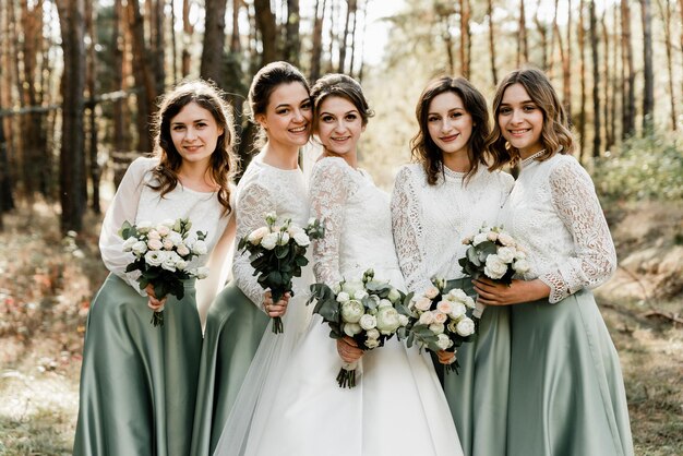 Beautiful bride with her pretty bridesmaids,bridesmaids with a bride hugging and laughing cheerfully, happy wedding day, wedding bouquet, holiday of newlyweds