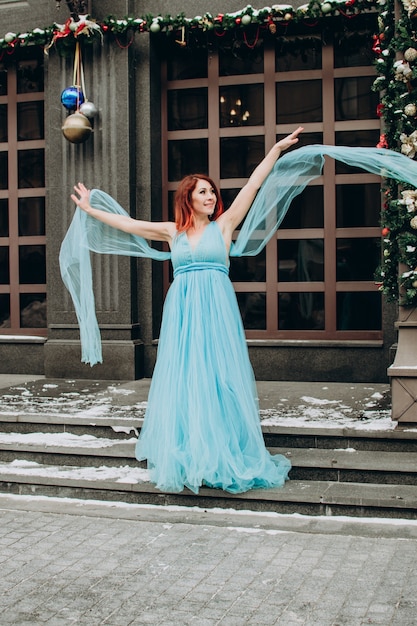 街の背景に青い長いドレスの赤い髪の美しい花嫁
