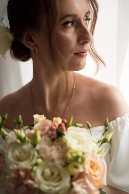 Foto bella sposa con bouquet da sposa vicino alla finestra