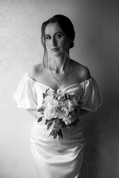 Beautiful bride with wedding bouquet near window