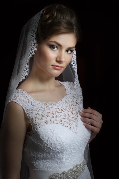 Beautiful bride with a wedding hairstyle on a dark background