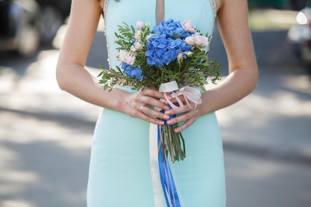 Foto bella sposa o donna tenere bouquet da sposa di fiori blu primo piano portarait sullo sfondo