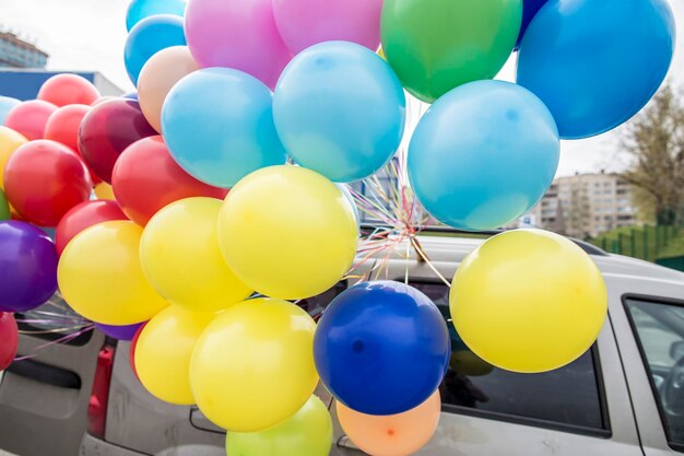 Beautiful bright bunch of colorful balloons fixed to the roof of the car