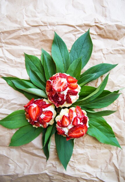 Beautiful and bright cupcakes with strawberries lie on green leaves