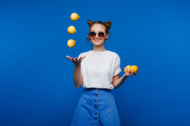 Beautiful bright girl in retro style, throws up yellow lemons. Happy girl