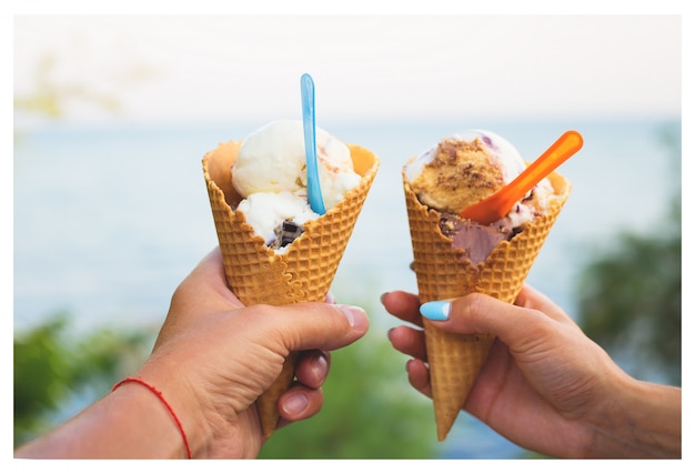 カップルの手にさまざまなフレーバーを持つ美しい明るいアイスクリーム