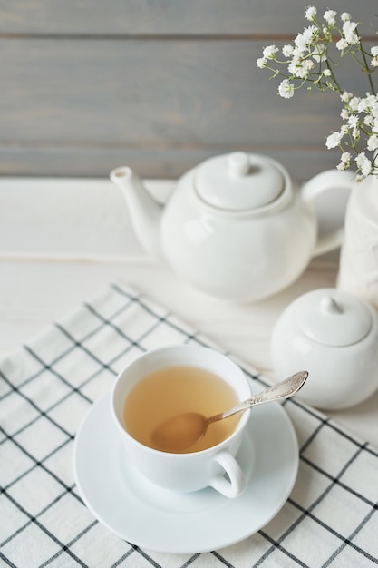 Beautiful bright tea set up. White ceramic tea pots and tea ingredients, on top of the white table.