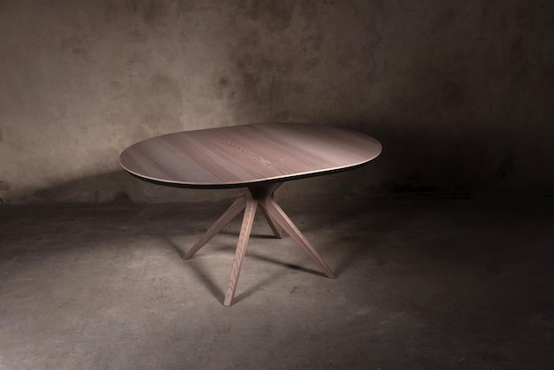 Beautiful brown wooden folding table on beige concrete background. Beautiful furniture in a modern interior