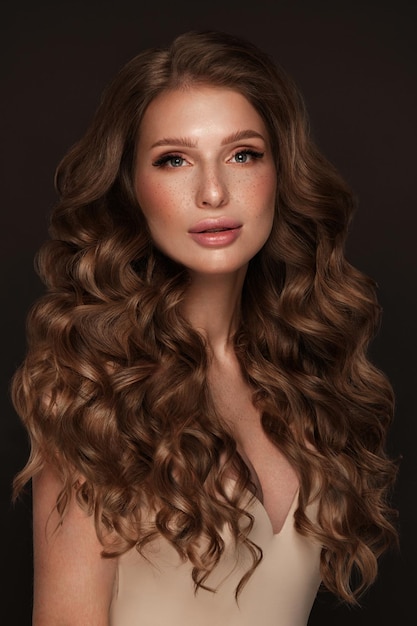 Foto bella ragazza dai capelli castani con i capelli perfettamente ricci e trucco classico bellezza viso e capelli