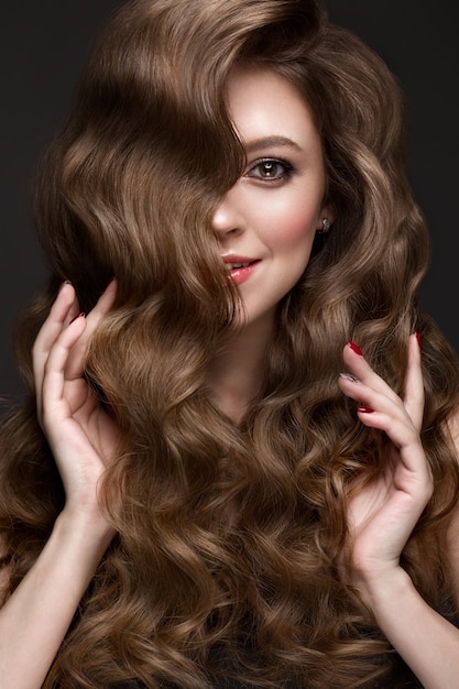 Bella ragazza dai capelli castani con capelli perfettamente ricci e trucco classico