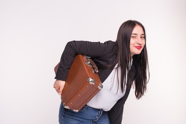 Beautiful brunette asian girl holding old-fashioned suitcase on white.