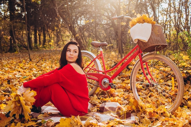 Beautiful brunette in the autumn forest with a bicycle