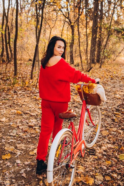 Beautiful brunette in the autumn forest with a bicycle