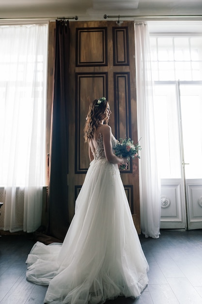 Beautiful brunette bride in a luxurious wedding dress in rich vintage interior