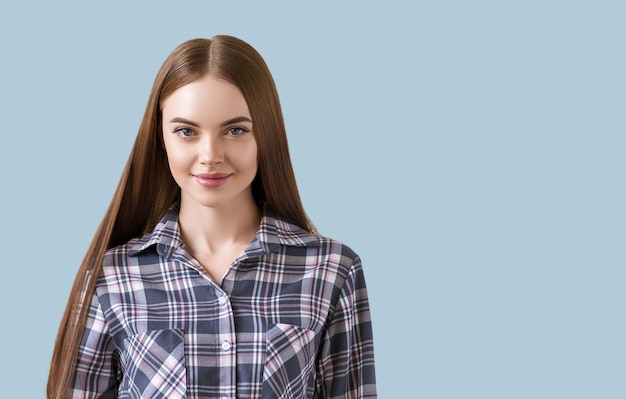 Beautiful brunette in check dress natural portrait. Color background. Blue