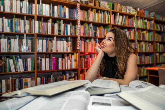 美しいブルネットは、スマートな本を読むために週末に図書館に来ます図書館の女性の概念