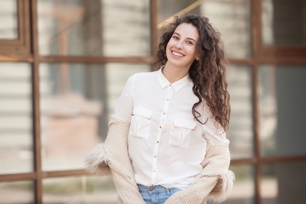 Beautiful brunette curly woman smiling outdoors