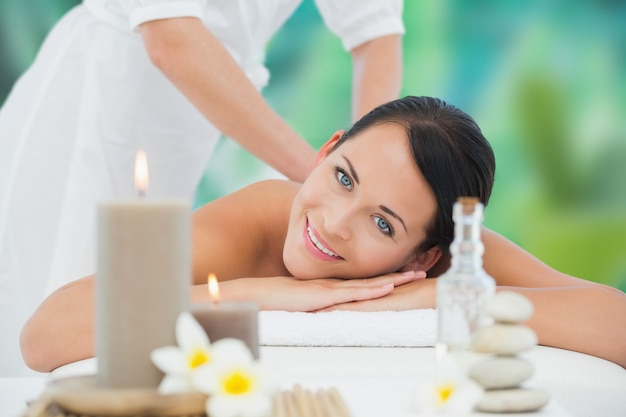 Beautiful brunette enjoying a back massage smiling at camera